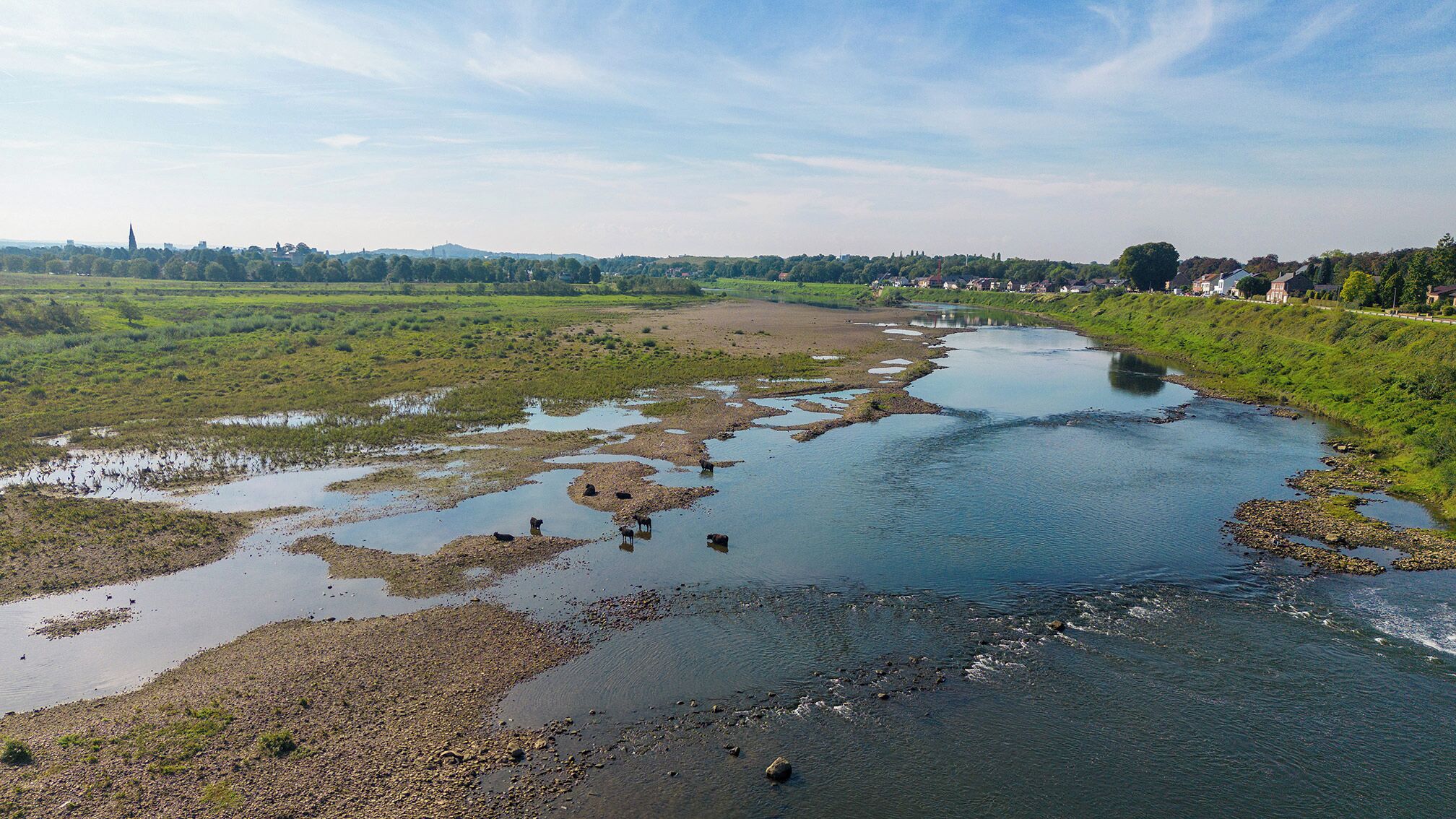 Un río con vegetación circundante y un pueblo distante.