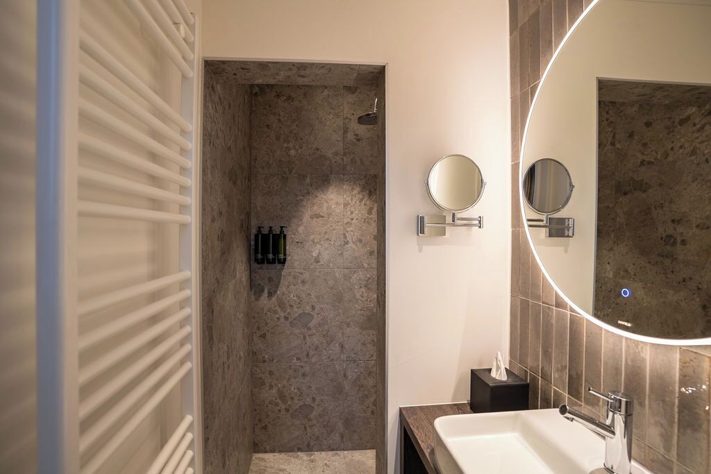 A modern bathroom with a walk-in shower, a large mirror, and a vanity with a sink.