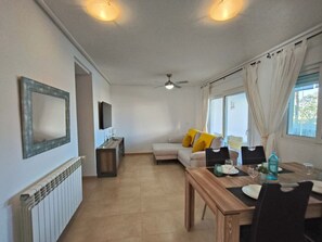 Ein modernes Wohnzimmer mit einer Couch, einem Esstisch und einem Fernseher.