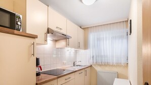 A compact kitchen with a microwave, sink, and window with sheer curtains. - Lovely apartment for 6 guests with WIFI, TV, terrace and pets allowed (Mayrhofen)