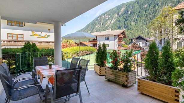 A balcony with outdoor seating, a view of a mountain, and a building with a balcony in the background. - Lovely apartment for 6 guests with WIFI, TV, terrace and pets allowed (Mayrhofen)