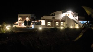 A modern two-story building with a staircase leading to the upper floor, surrounded by well-lit areas and a few plants. - The Tiger Claws Tadoba (Chimur)