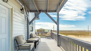 Une terrasse en bois avec des sièges extérieurs, un espace abrité et une vue sur la plage.