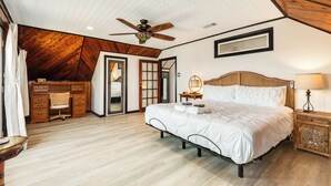 Une chambre à coucher comprenant un lit, un bureau, une chaise, un ventilateur de plafond et une table de chevet avec une lampe.