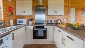 Cocina compacta con paredes de madera, extractor de acero inoxidable, microondas, tostadora y lavamanos.