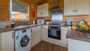 Cocina compacta con paredes de madera, lavadora, microondas, cocina y tostadora.