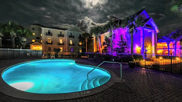 A swimming pool with a 3 FT depth marker, surrounded by a brick walkway and a fence.