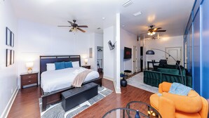 A modern bedroom with a bed, bedside tables, a ceiling fan, and a seating area with a sofa and armchair.