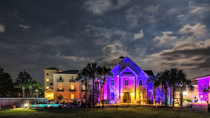 A hotel with a well-lit entrance, a swimming pool, and a large building with colorful lighting.