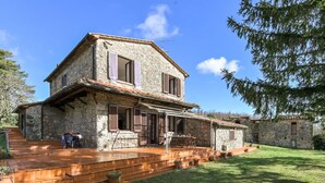 A stone house with a wooden staircase leading to a covered porch. - Stunning private villa for 8 guests with WIFI, TV, patio and pets allowed (Montieri)