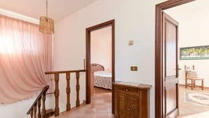 A hallway with a staircase, a bed, a wooden cabinet, and a door leading to another room. - Stunning private villa for 8 guests with WIFI, TV, patio and pets allowed (Montieri)