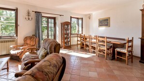 A spacious living room with a large sofa, a dining table with chairs, and a cabinet with glass doors. - Stunning private villa for 8 guests with WIFI, TV, patio and pets allowed (Montieri)