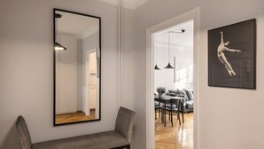 A hallway with a bench, a large mirror, and a framed artwork on the wall. - ShortStayPoland Piwna B79 (Warsaw)