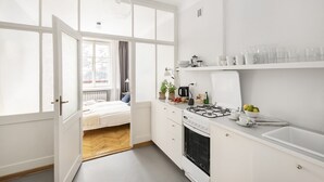 A bright kitchen with a large window, white cabinets, and a stove. - ShortStayPoland Piwna B79 (Warsaw)