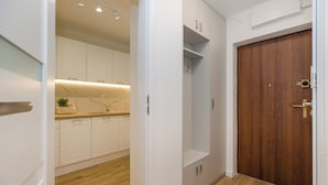 Uma cozinha moderna com armários brancos, painel de backsplash de mármore e piso de madeira.