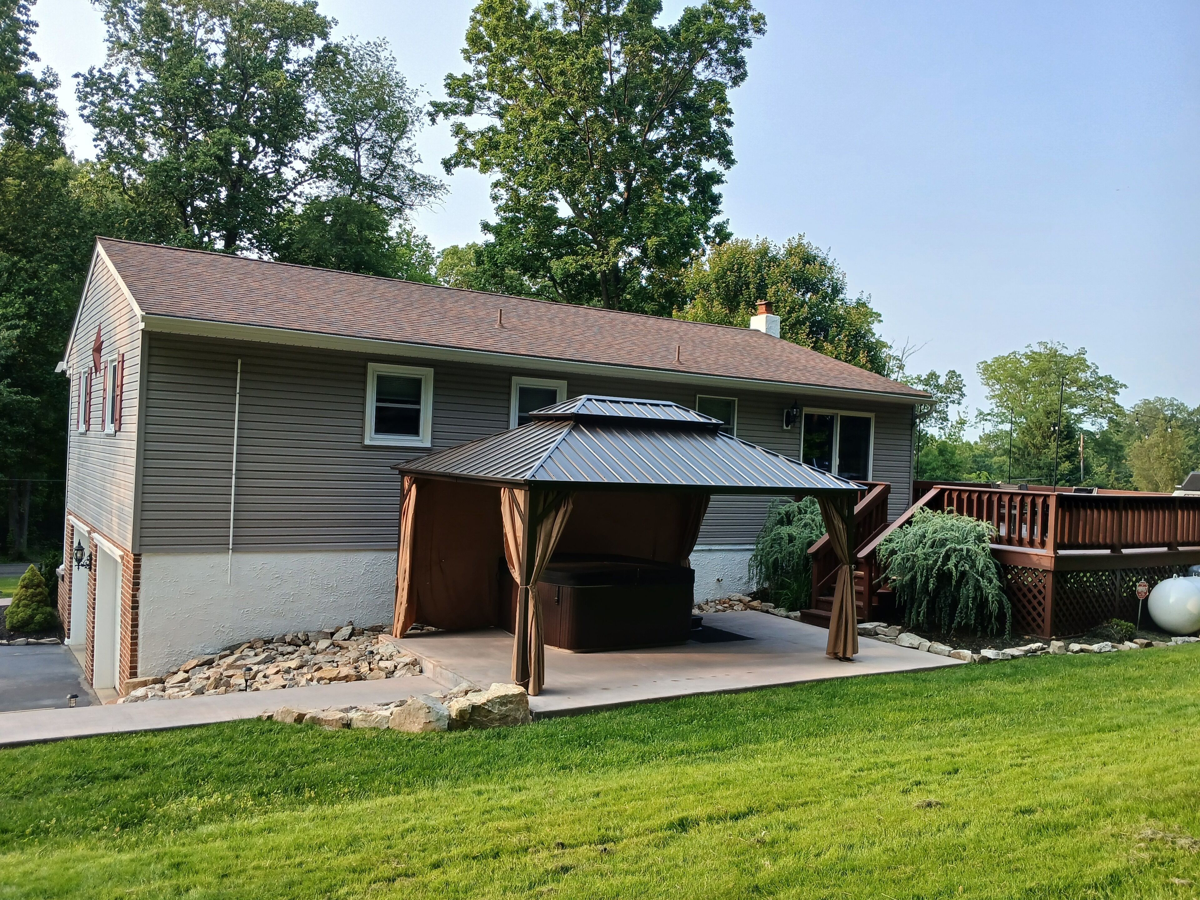 A two-story house with a covered patio area and a stone retaining wall.