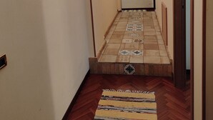 Un pasillo con alfombra estampada, cuadros enmarcados y suelo de baldosas que conduce a una puerta.