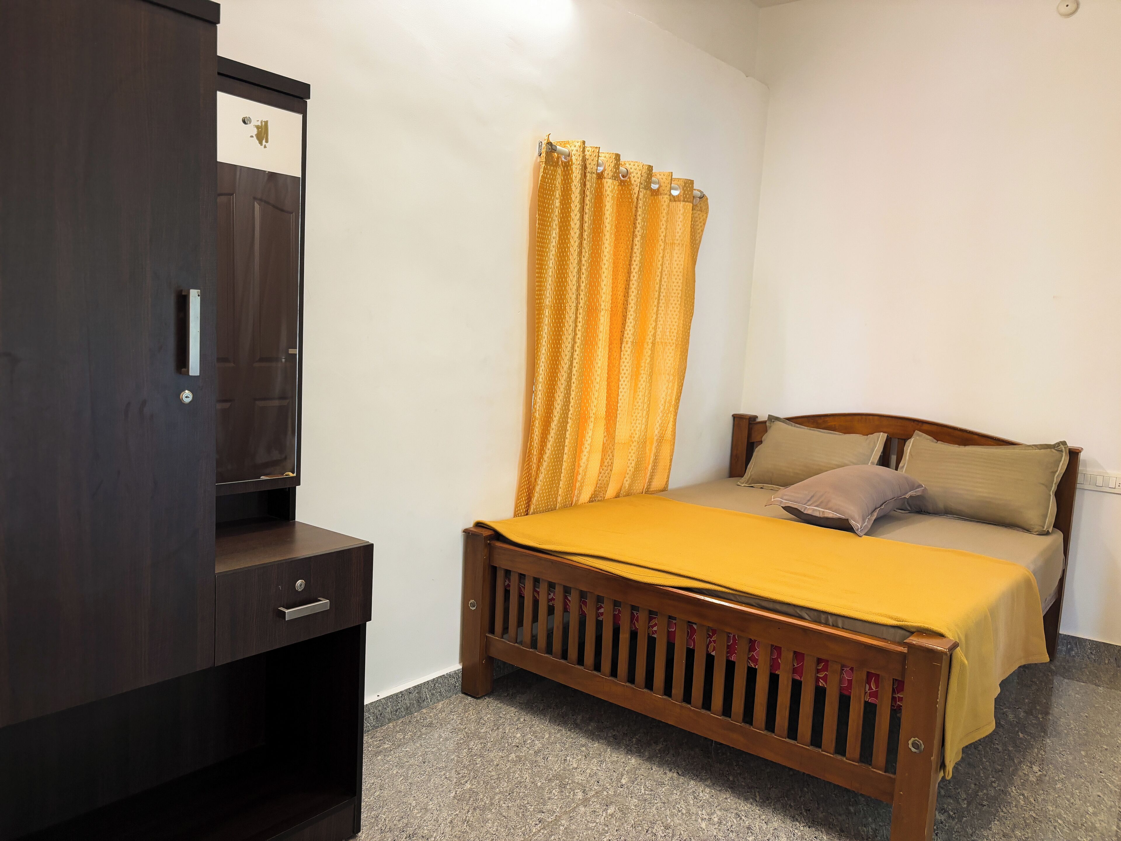 A bedroom with a wooden bed, a nightstand, a wardrobe, and a yellow curtain.