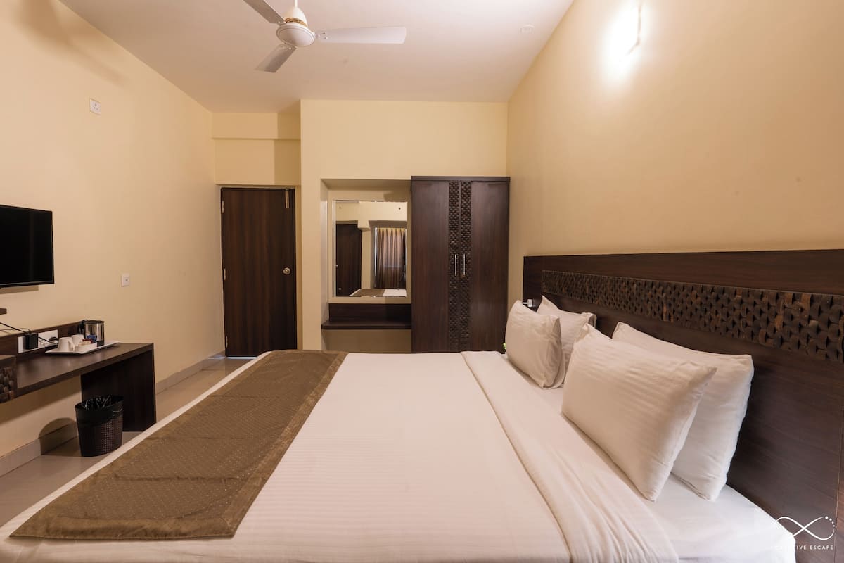 A hotel room with a bed, a desk, a television, and a wardrobe.