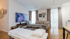 Una sala de estar moderna con un sofá, una cama, un televisor y obras de arte en las paredes.