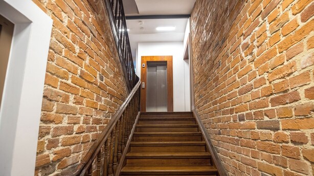 Una escalera de madera con paredes de ladrillo y barandilla de madera.