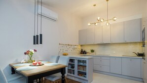 Una cocina moderna con armarios grises claros, una mesa de comedor de madera y una lámpara colgante.