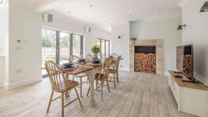 A spacious dining area with a wooden table and chairs, a fireplace, and a television.