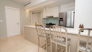 Una cocina moderna con una isla central, electrodomésticos de acero inoxidable y encimera blanca.