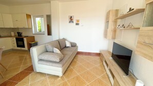 A modern living room with a sofa, TV, and kitchen area.