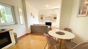 A compact kitchen with a dining area, a built-in oven, and a small trash bin.