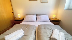 A double bed with two pillows, a nightstand with a lamp, and a wall with two framed artworks.