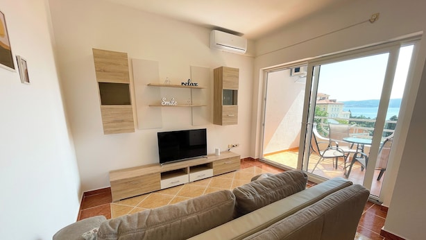 A modern living room with a flat-screen TV, wooden cabinets, and a sofa.