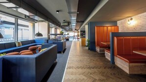 A modern lounge area with blue seating, wooden flooring, and a brick accent wall. - Student Only Clyde Court (Glasgow)