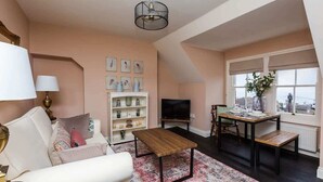 A living room with a sofa, coffee table, TV, and a dining area with a table and chairs.