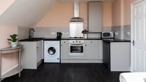 A compact kitchen with a washing machine, oven, microwave, and a small sink.