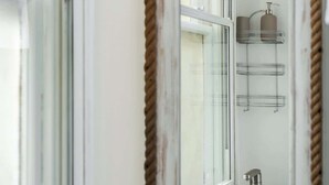 Un baño con espejo, ventana y lavamanos.