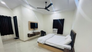 A modern bedroom with a bed, a TV, a ceiling fan, and an air conditioning unit. - HOTEL RAJDEEP (Sehore)