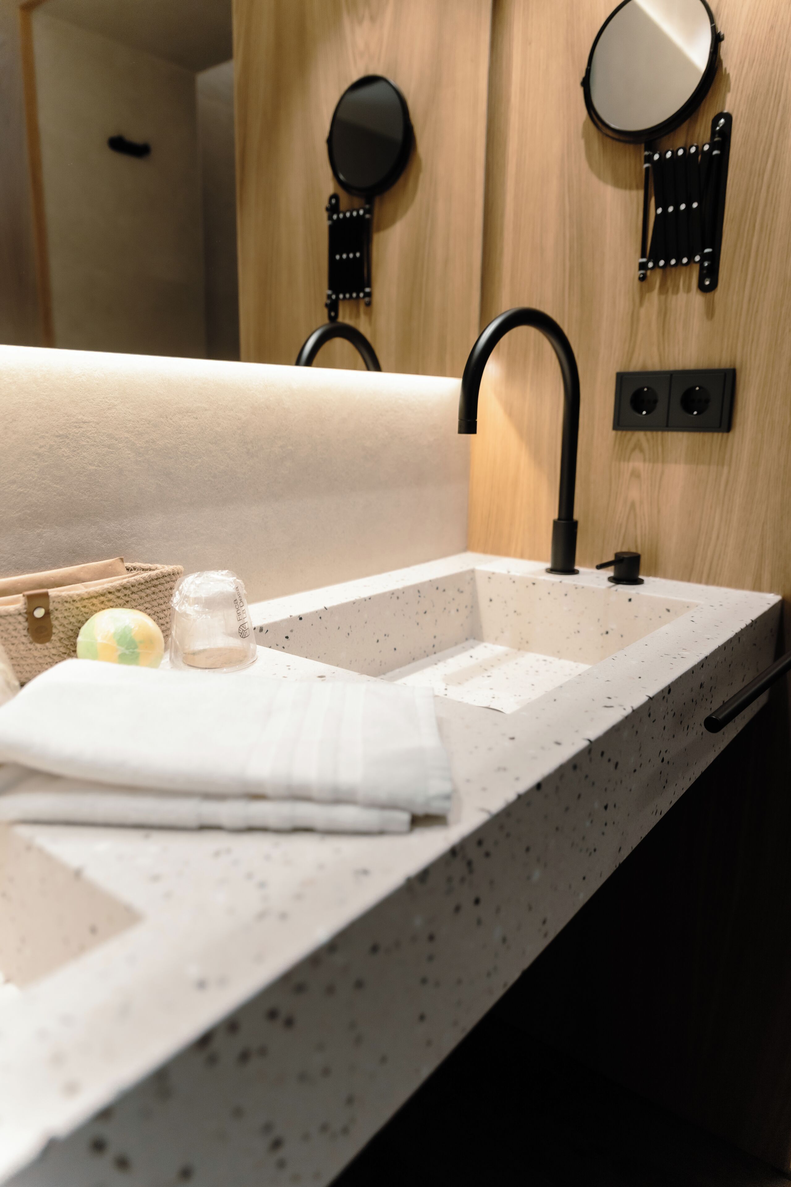 A bathroom with a speckled countertop, a black faucet, and two wall-mounted mirrors.