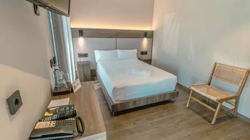 Une chambre d’hôtel avec un lit, une table de chevet en bois, un téléphone, une chaise et un miroir.