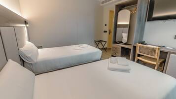 Een hotelkamer met twee bedden, een bureau, een stoel, een spiegel en een televisie.