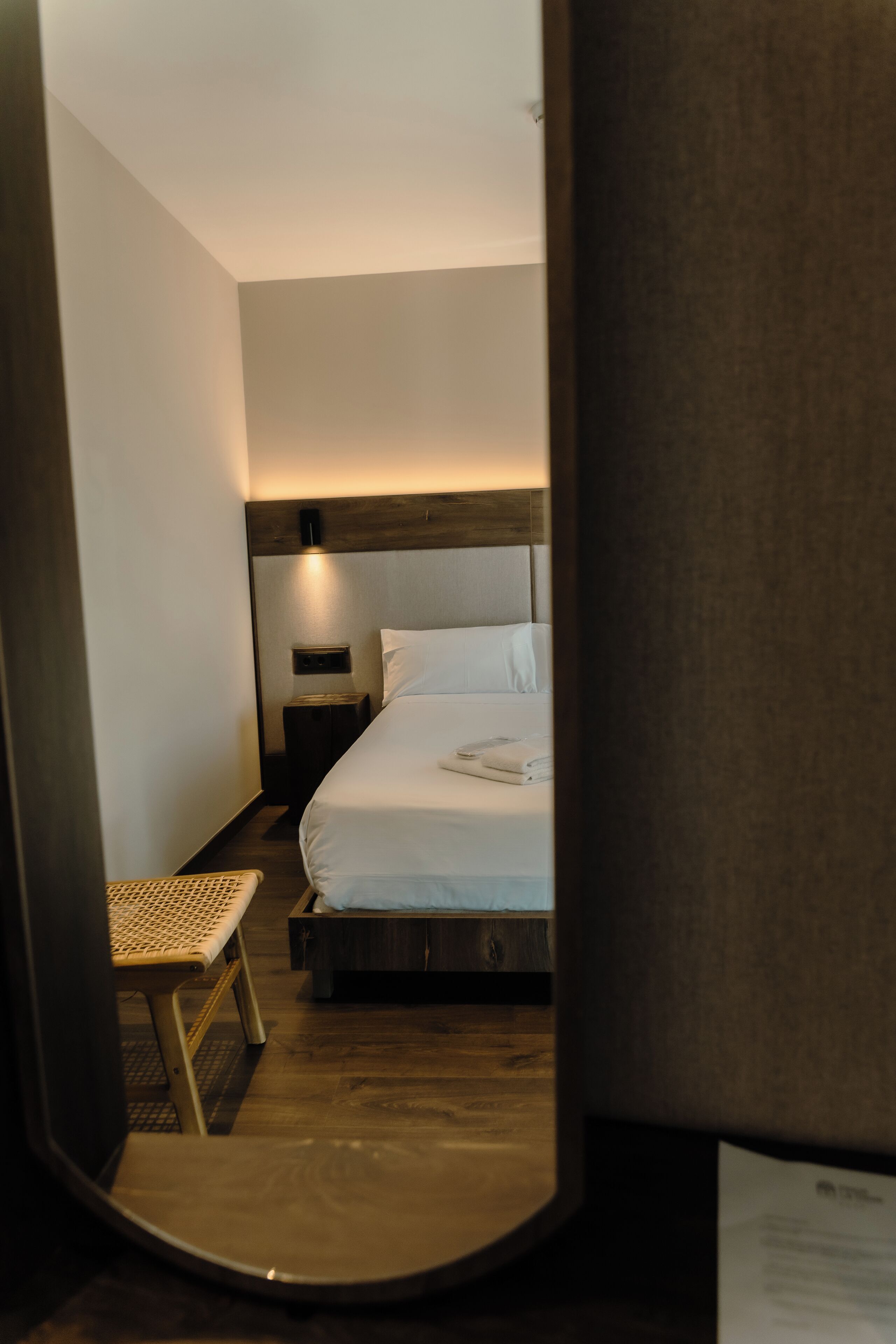 Ein Hotelzimmer mit Bett, Nachttisch und kleinem Hocker.