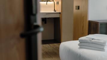 Una habitación de hotel con una cama, una mesita de noche, una lámpara y suelo de madera.