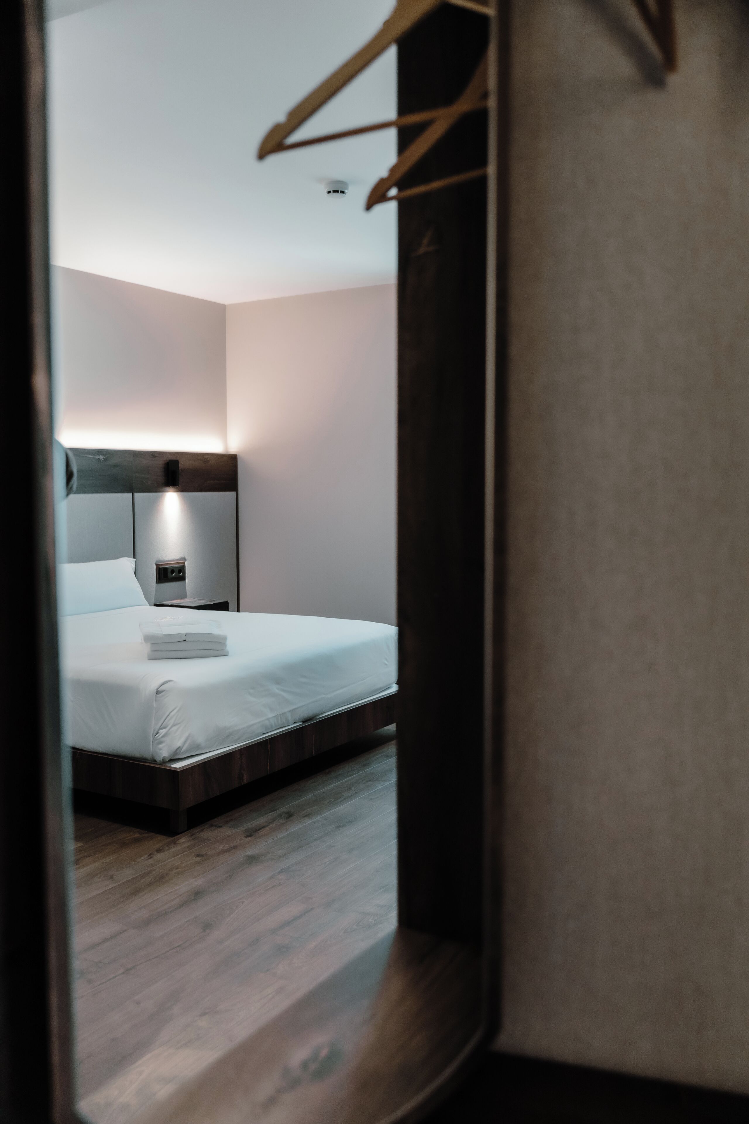 A bedroom with a bed, bedside table, and a hanging light fixture.