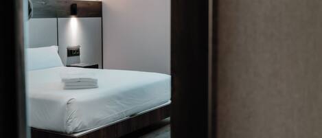 A bedroom with a bed, bedside table, and a hanging light fixture.