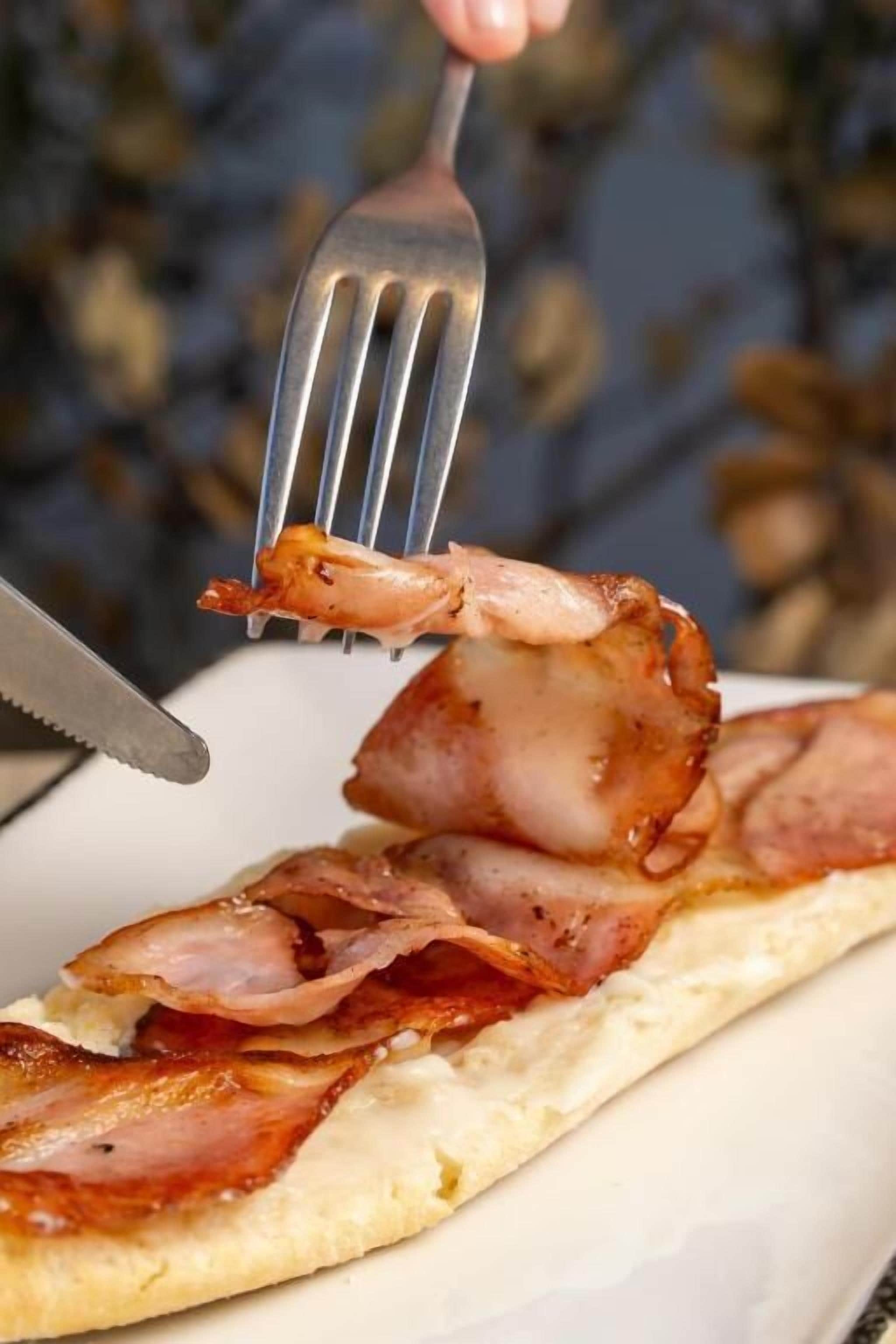 A breakfast plate with bacon and a piece of shrimp.