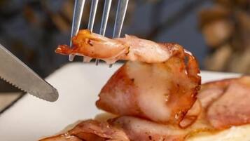 A breakfast plate with bacon and a piece of shrimp.