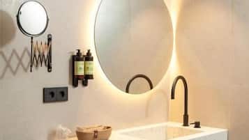 A modern bathroom with a freestanding sink, a round mirror, and a wall-mounted light fixture.