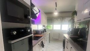 A modern kitchen with white cabinets, black appliances, and a tiled floor.