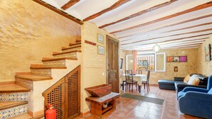 A living room with a blue sofa, wooden staircase, and a dining area with a table and chairs.
