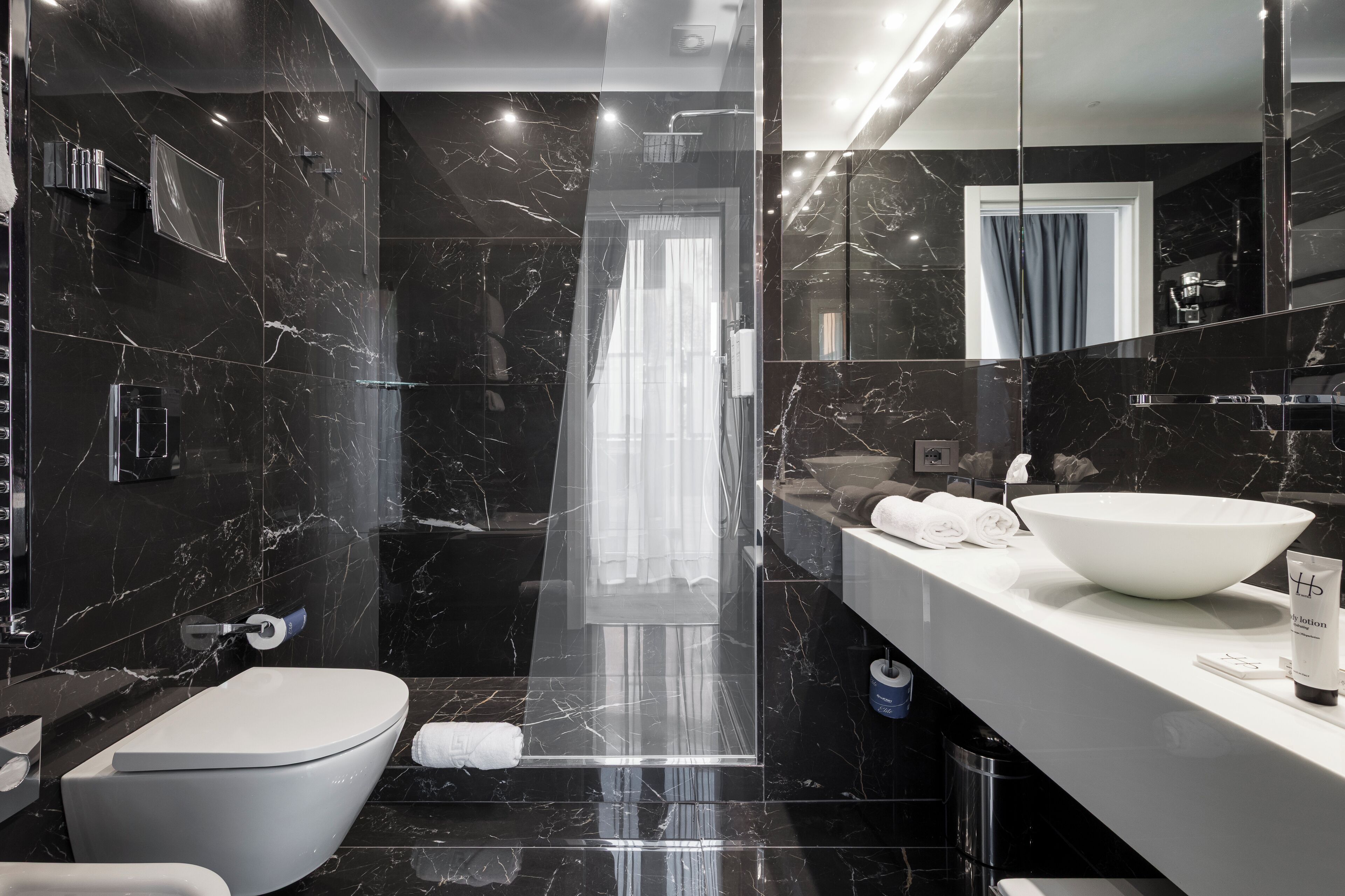 A modern bathroom with a large mirror, a white sink, and a bathtub.